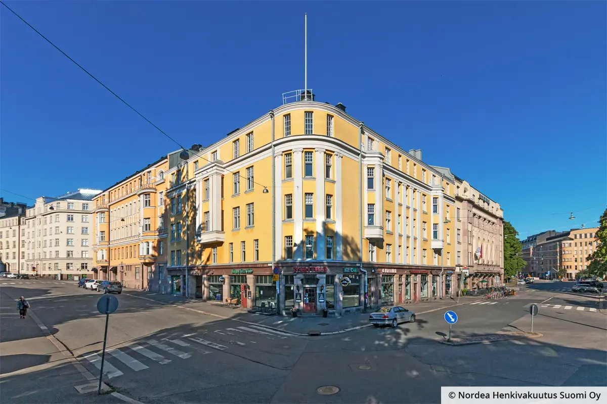 Helsingin Museokatu 8 keltainen julkisivu, jota koristavat joonialaiset pylväät. Katutasossa on liiketiloja, kulmassa jazzklubi.