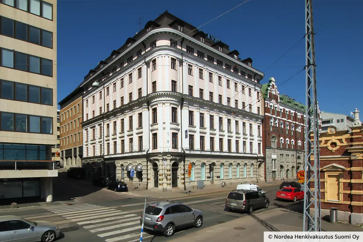 Helsingin Eteläranta 12 koristeellinen julkisivu. Katutasossa on kivinen fasaadi, jonka ovien ja ikkunoiden päällä on holvikaaret.
