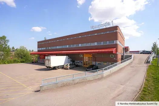 Vantaan Muuntotie 1 julkisivu ovien A2 ja A3 puolesta. Katutasossa on nosto-ovi, ajoramppi pihan toiseen kerrokseen ja sen vieressä kulku pohjakerroksen tiloihin.