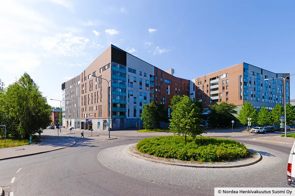 Helsingin Vanhalinna suuri julkisivu liikenneympyrän laidalla. Kahdeksankerroksinen kulmikas rakennus koostuu punatiilisistä ja vaaleista osista.