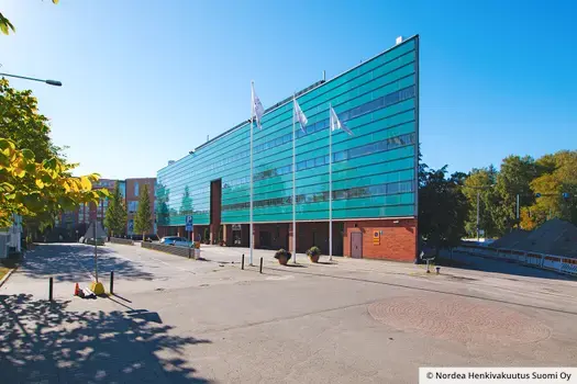 Toimitilakiinteistö Helsingin Strömberginkuja 2 on kolmion muotoinen rakennus, jossa on kaksi punatiilistä seinää ja turkoosi lasiseinä.