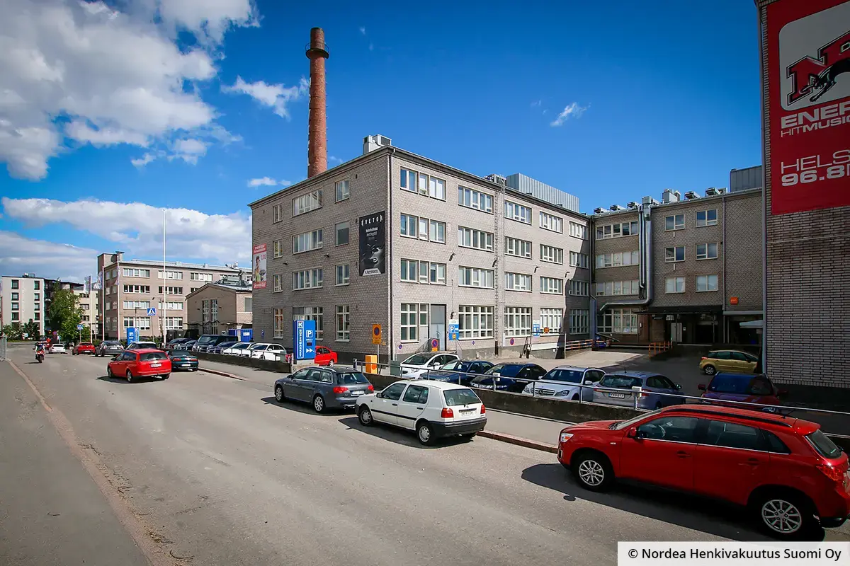Toimitilakiinteistö Kiviaidankatu 2, Helsinki, keskiosa kuvattuna kadulta, taustalla vanha savupiippu.