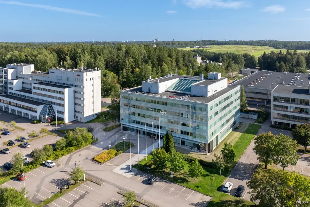 Turkoosin värinen toimitilakiinteistö Sinihelmi Business House ilmasta kuvattuna. Taustalla näkyy Tapiolan golfkenttä.