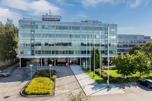 Sinihelmi Business House suoraan talon edestä kuvattuna. Keskellä taloa on lasiset pariovet, jotka johtavat talon pääaulaan ja edelleen toimitiloihin.