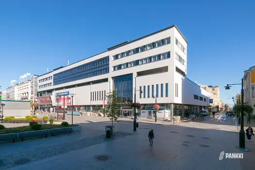 Vaalean toimitilakiinteistön alakerrassa on liiketiloja ja ylemmissä kerroksissa toimistoja.