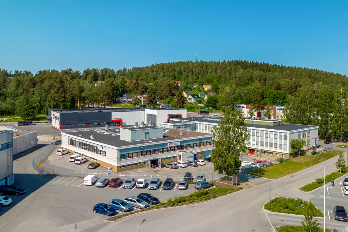 Jyväskylän Onkapannu 2 toimitilakiinteistö ilmasta kuvattuna. Matalan vaalean rakennuksen ympärillä on pysäköintipaikkoja.