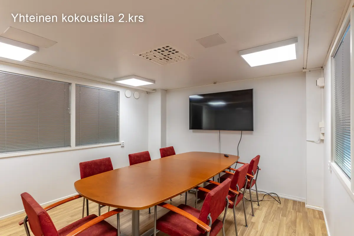 Jyväskylän Onkapannu 2:n 2. kerroksen kokoustila, jossa puinen pöytä ja 7 punaista kokoustuolia.