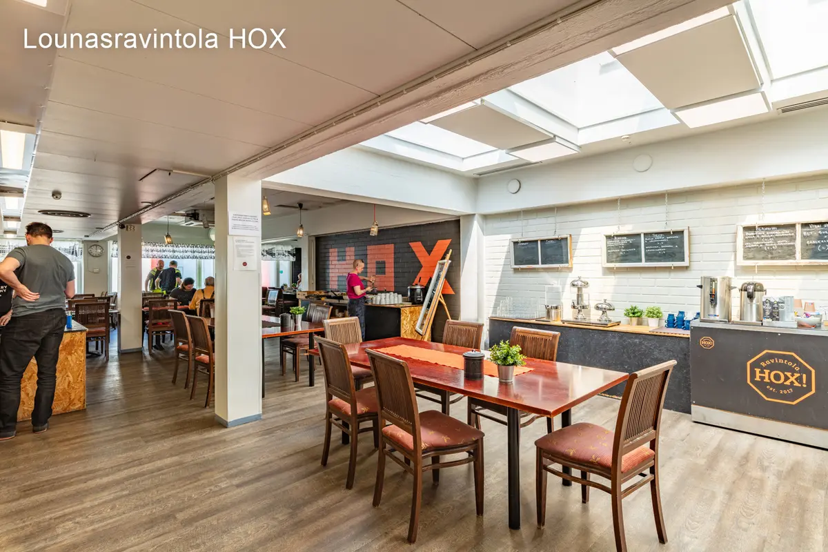 Jyväskylän Onkapannu 2:ssa sijaitseva lounasravintola HOX. Ravintolasalissa on ihmisiä syömässä puisten ruokapöytien ääressä.