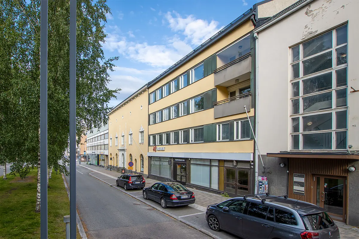 Jyväskylän Yliopistonkatu 28:n keltainen julkisivu. Rakennuksen edessä on autoja pysäköitynä kadunvarteen.