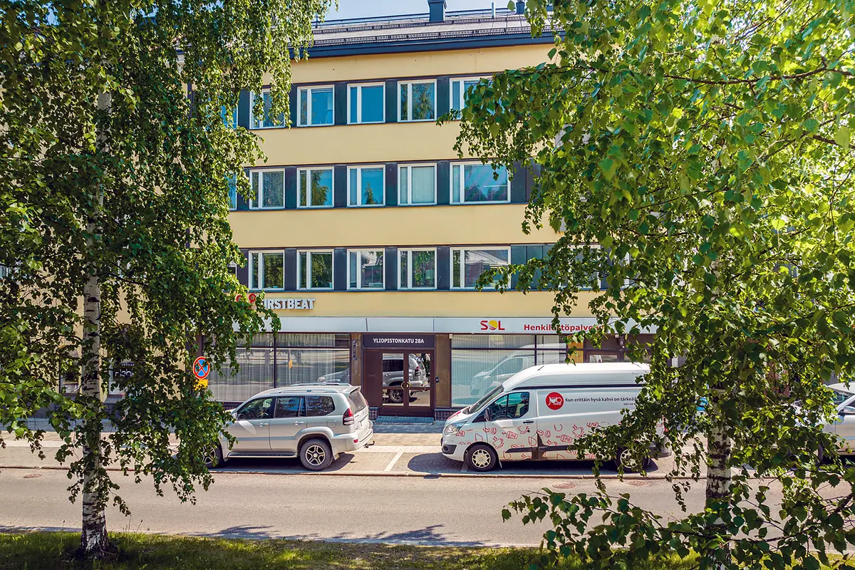 Jyväskylän Yliopistonkatu 28:ssa sijaitseva nelikerroksinen toimitilakiinteistö. Etualalla on koivuja.