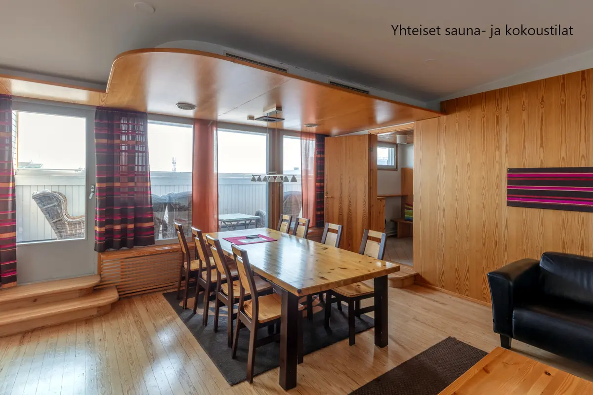 Jyväskylän Yliopistonkatu 28:n kokoustilassa on 8 hengen puinen pöytä. Suuresta ikkunasta näkyy terassi.
