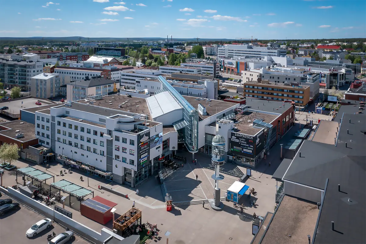 Sampokeskus- kauppakeskuskiinteistö Rovaniemen keskustassa ilmasta kuvattuna. Rakennuksen sisäänkäynnin edessä on pieni tori.