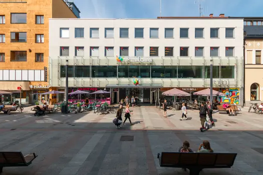 Kauppakortteli Pekurin sisäänkäynti kävelykadun puolella. Rakennuksen edessä on terassi, jossa on aurinkovarjoja.