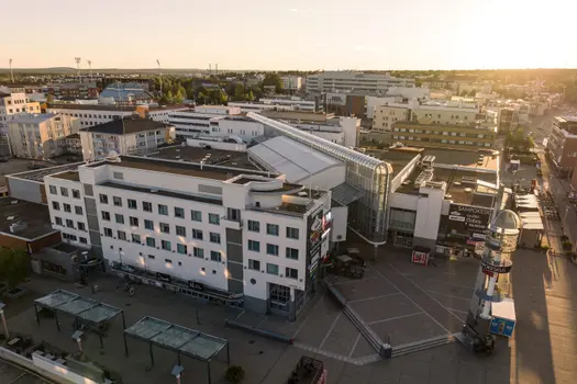 Kaupungin keskustan noin viisikerroksisia toimitila- ja kerrostaloja ilmasta kuvattuna auringonlaskun aikaan.