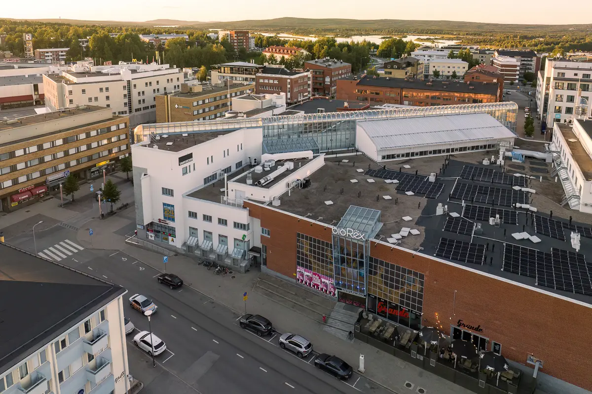 Toimitila- ja kerrostalorakennuksia Rovaniemen keskustassa. Etualalla Bio Rex. Taustalla kaupungin vehreää luontomaisemaa.