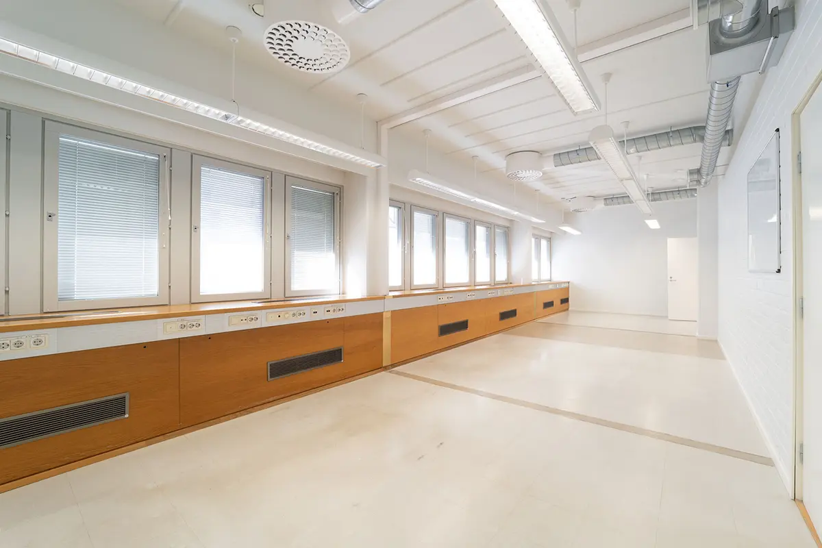 Jyväskylän Yliopistonkatu 28 ensimmäisen kerroksen 193 m2 toimitilan valoisa avotoimistotila. Seinustalla ikkunat, ilmanvaihto ja pistokkeet, vastapäätä ovet käytävälle.