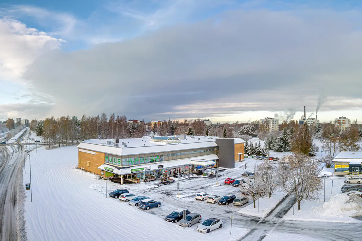 Porin Herralahdenraitti 1 talvisessa ilmakuvassa. Kaksikerroksinen liikerakennus, jonka edessä pysäköintialue.