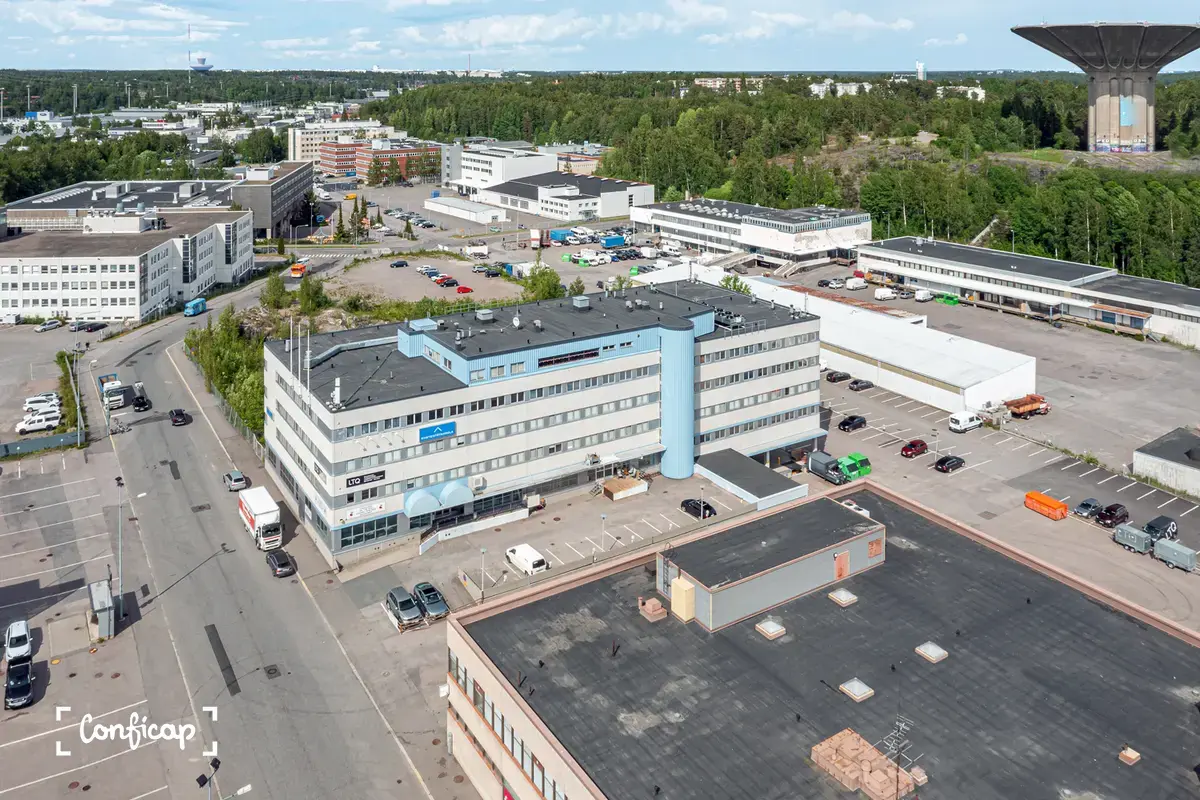 Kiinteistö kuvattuna ilmasta, vasemmalla puolella tie. Rakennuksien oikealla puolella metsikkö ja vesitorni.