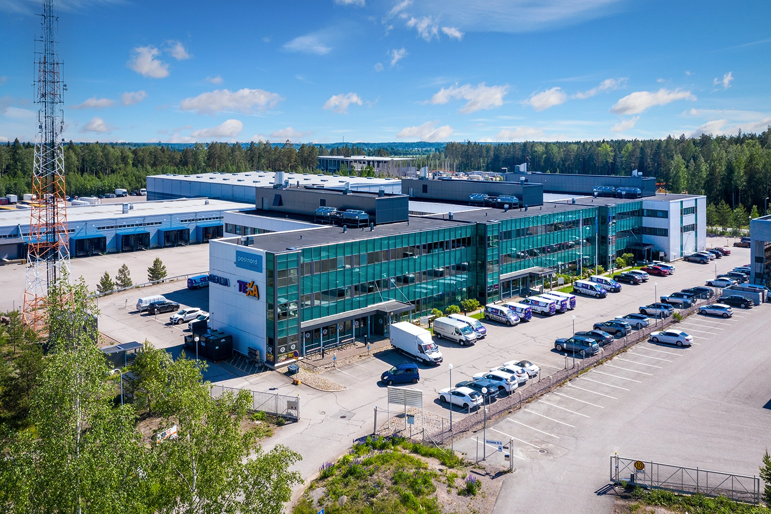 Vantaan Ansatie 6 -toimitilakiinteistu00f6 ilmasta kuvattuna. Matalan, pitku00e4n rakennuksen edessu00e4 on pysu00e4ku00f6intialue.