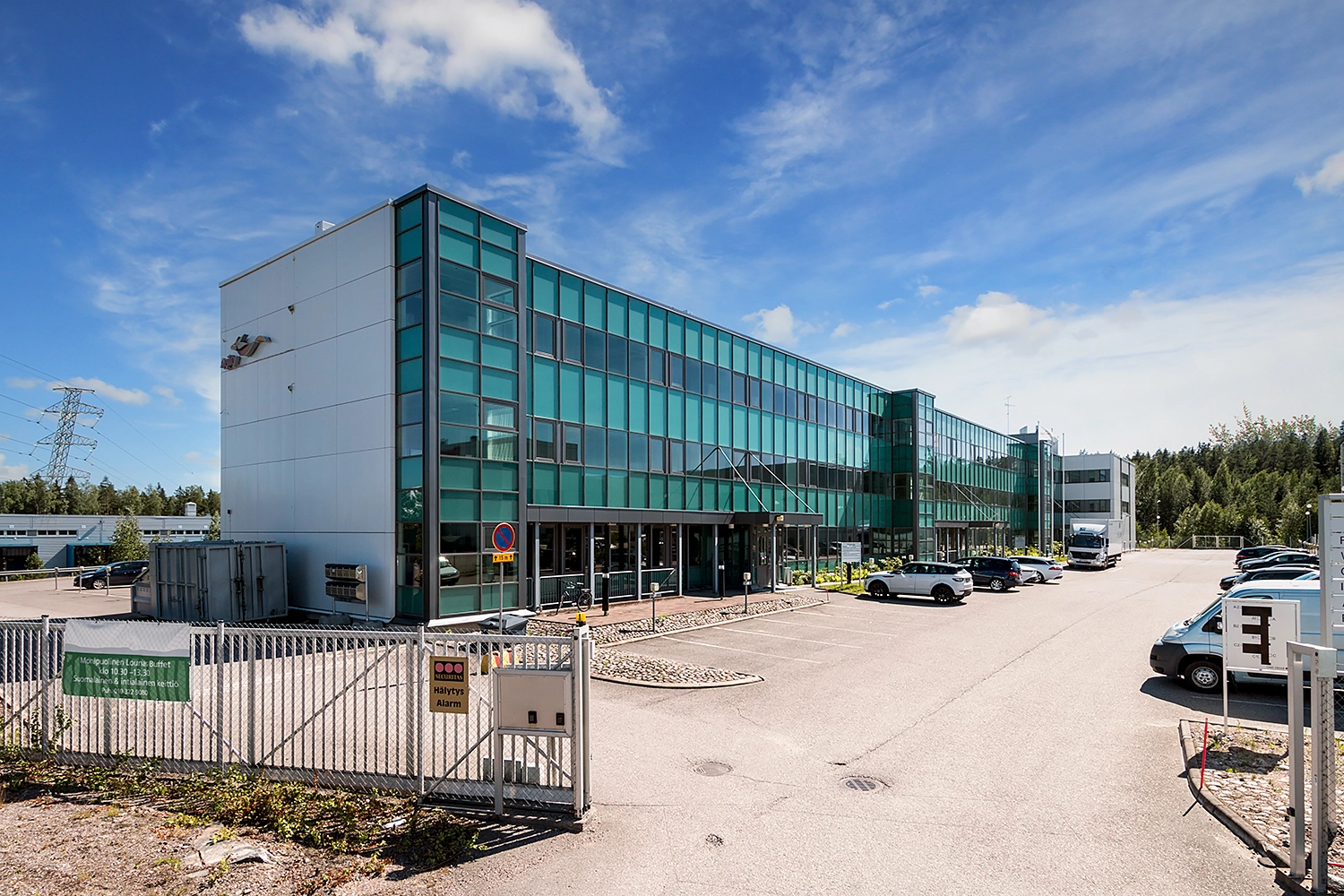 Vantaan Ansatie 6 -toimitilakiinteistu00f6n julkisivu. Matalassa rakennuksessa on vihreu00e4nsu00e4vyinen lasiseinu00e4.