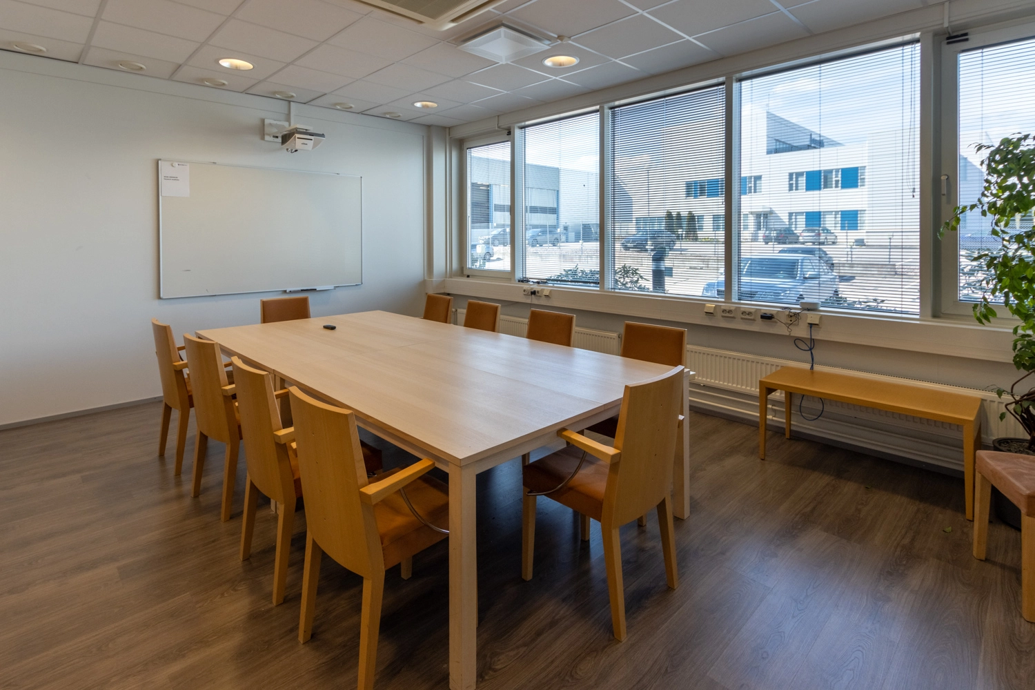 Toimitilakiinteistu00f6n neuvotteluhuoneessa on kokuspu00f6ytu00e4 ja 10 tuolia sen ympu00e4rillu00e4. Seinu00e4llu00e4 on piirustustaulu.