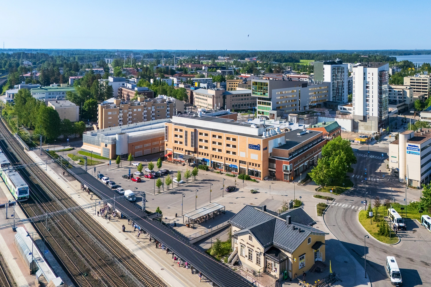 Ju00e4rvenpu00e4u00e4n juna-aseman seutua ilmasta kuvattuna. Asemarakennus on vanha pieni puinen, sen takana on pysu00e4ku00f6intialue ja kaupungin muita kerros- ja toimitilarakennuksia. Etualalla kulkee junaraide.