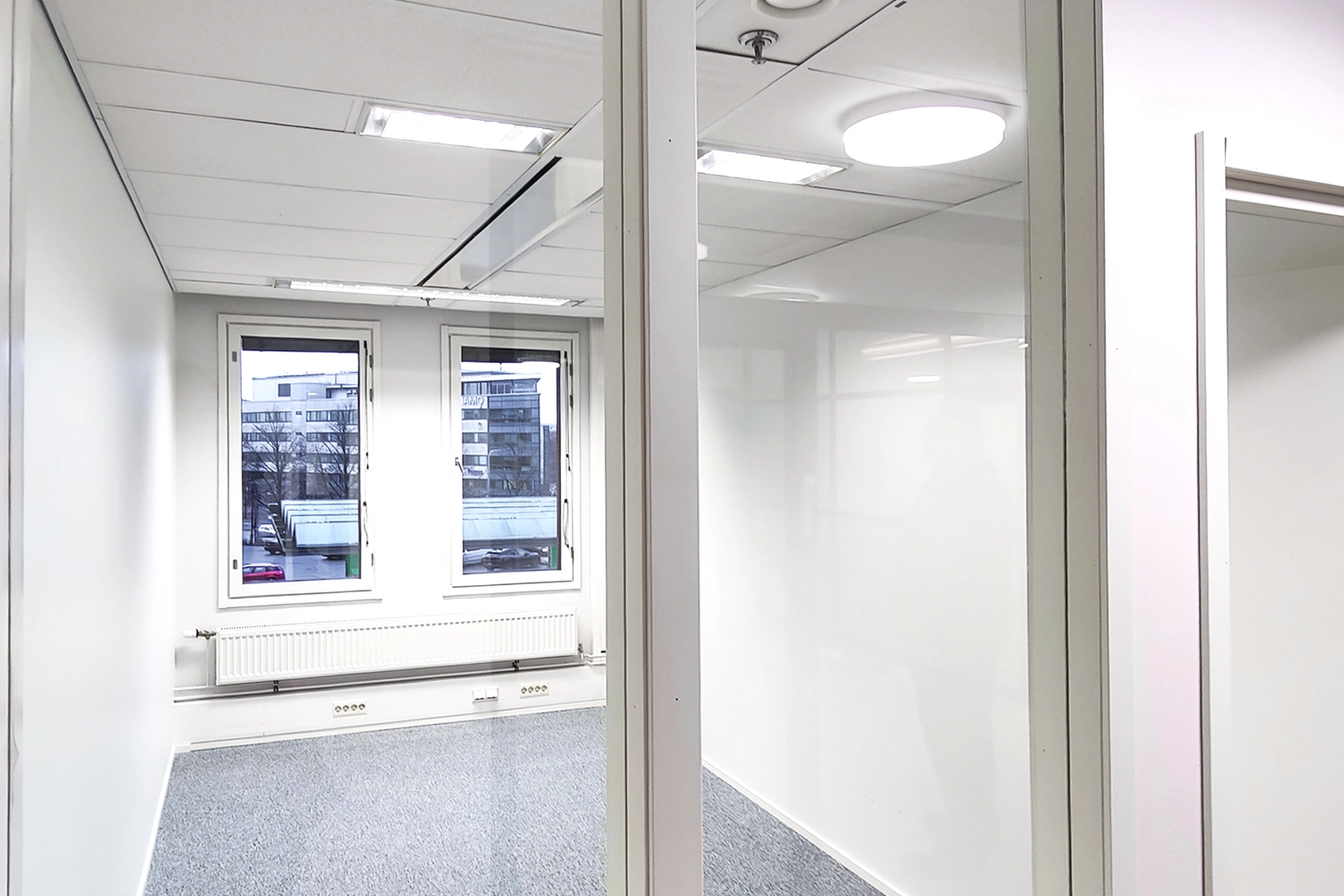 Tampereen Hatanpu00e4u00e4n valtatie 18 toimitilakiinteistu00f6ssu00e4 sijaitseva toimistohuone, jossa kaksi ikkunaa ja lasiseinu00e4 ku00e4ytu00e4vu00e4n suuntaan.