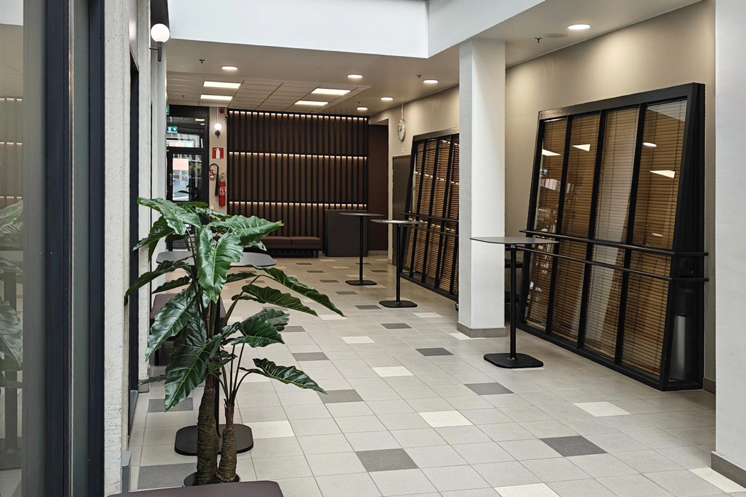 Tampereen Hatanpu00e4u00e4n valtatie 18 toimitilakiinteistu00f6n aula, jossa pystypu00f6ytiu00e4 ja huonekasveja.