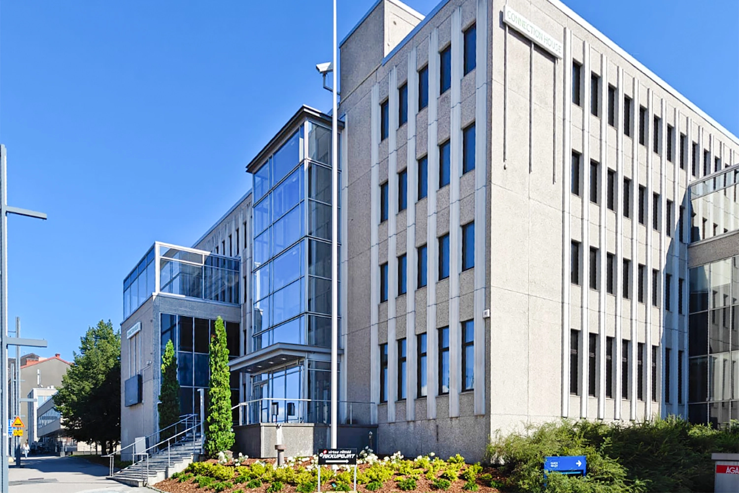 Tampereen Hatanpu00e4u00e4n valtatie 18 toimitilarakennus. Rakennuksen edessu00e4 lipputanko ja istutuksia.