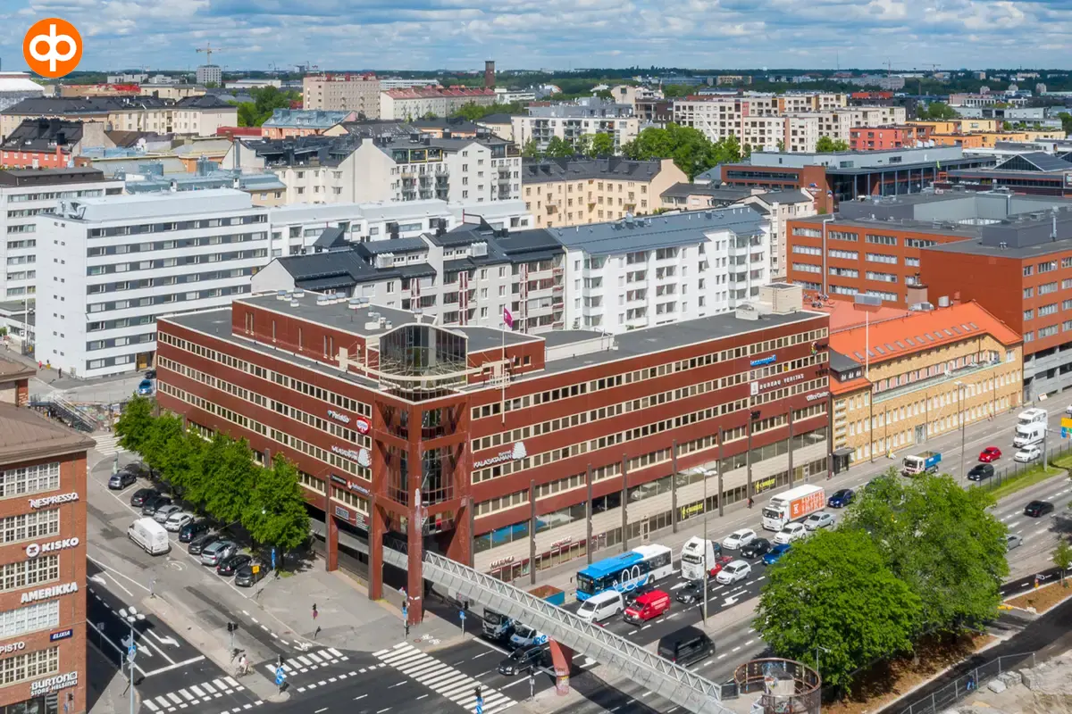 Kalasataman Kummelin toimitilakiinteistö ilmasta kuvattuna. Punatiilijulkisivuinen rakennus kadun kulmassa.