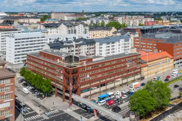 Kalasataman Kummelin toimitilakiinteistö ilmasta kuvattuna. Punatiilijulkisivuinen rakennus kadun kulmassa.