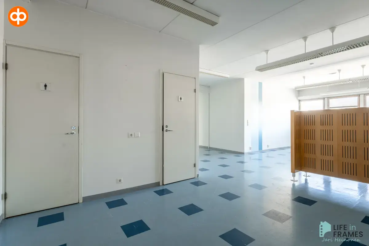 Bright business premises at Lauttakylänkatu 4 in Huittinen, where the open space is divided by a wooden screen. On the wall there are doors to the toilets.