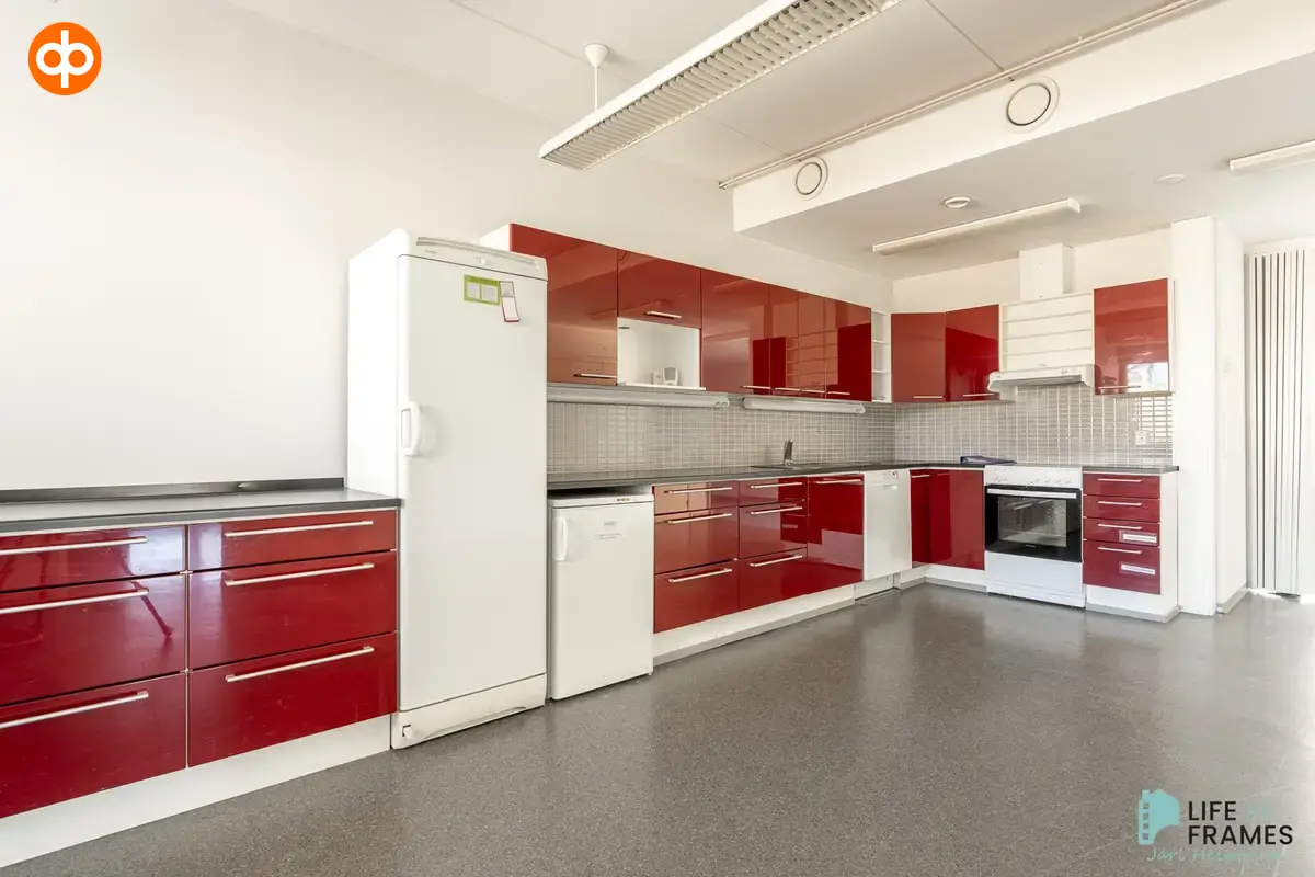 A large kitchen with shiny red cabinets in the 322,5 m² second floor premises at Lauttakylänkatu 4 in Huittinen.