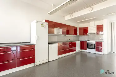 A large kitchen with shiny red cabinets in the 322,5 m² second floor premises at Lauttakylänkatu 4 in Huittinen.