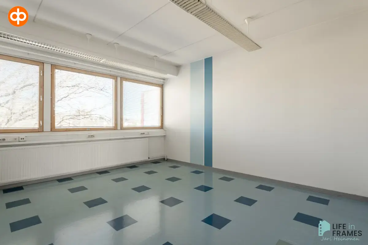 A bright open-plan space with windows, where the blue colours of the floor are repeated in the stripes painted on the wall. 