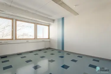 A bright open-plan space with windows, where the blue colours of the floor are repeated in the stripes painted on the wall. 