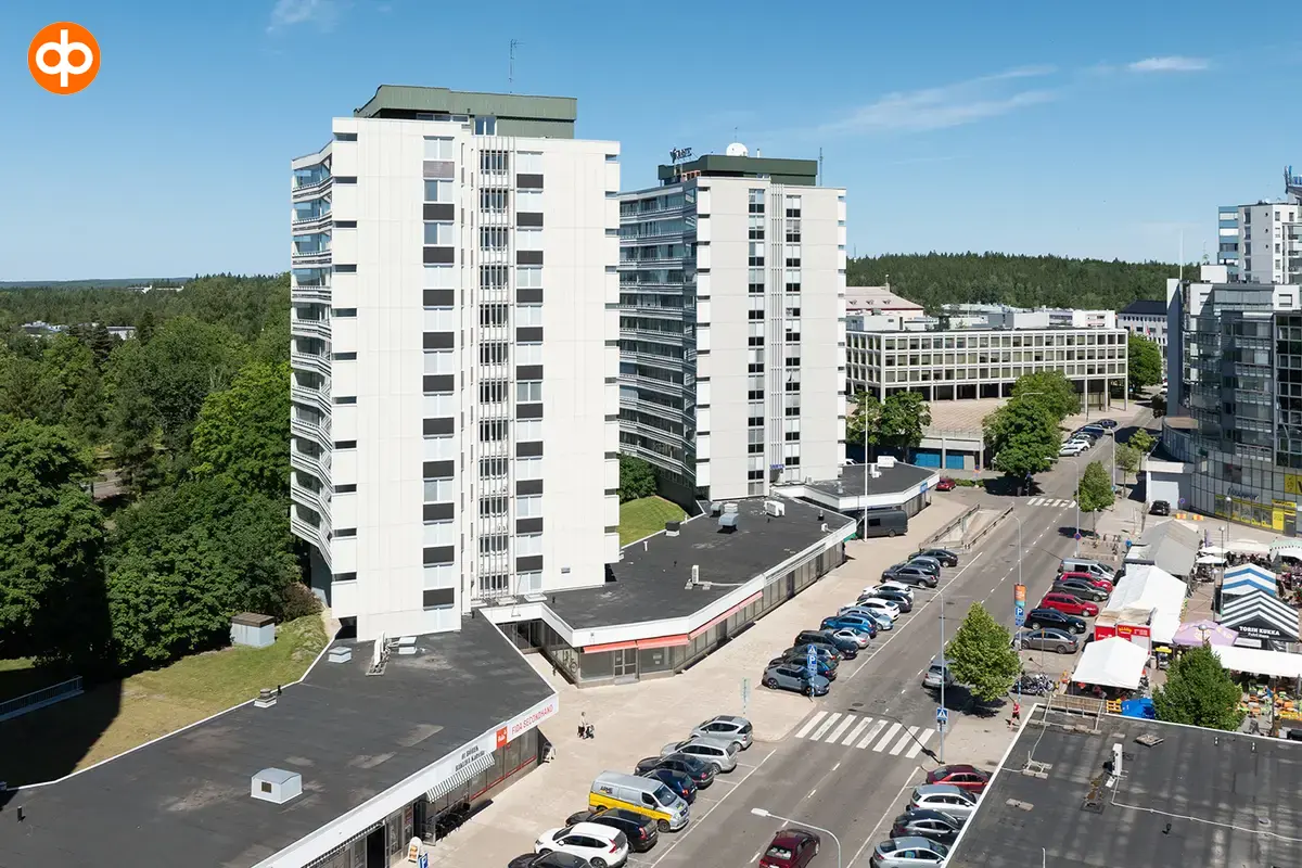 Ilmakuvassa katutason liiketiloja Torikatu 4. Kiinteistön edessä on parkkipaikkoja, ja matalan toimitilakiinteistön takana on korkeita asuinkerrostaloja.
