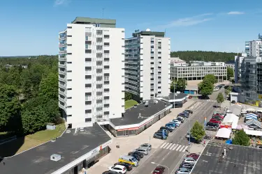 Ilmakuvassa katutason liiketiloja Torikatu 4. Kiinteistön edessä on parkkipaikkoja, ja matalan toimitilakiinteistön takana on korkeita asuinkerrostaloja.