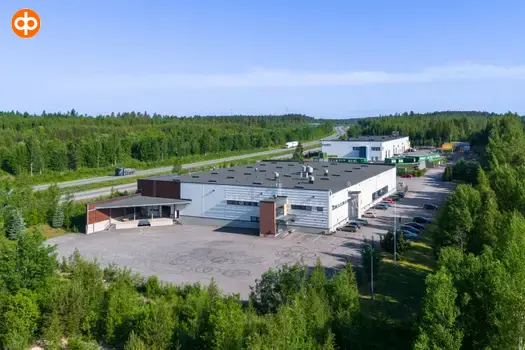 Järvenpää's Tempo 4, an exterior view of the office building. A white flat-roofed building, surrounded by a courtyard. Surrounded by forest and behind it a multi-lane road.