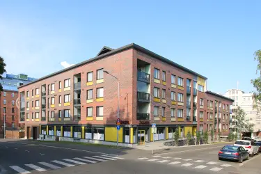 Kuopio Satamakatu 13 a, exterior view of the office property. A red brick multi-storey residential building. Commercial premises at street level.