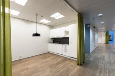 Alberga Business Park – D and E buildings, interior view of the 372.5 m2 office space on the 3rd floor. Alcove with a small kitchen with light cabinets. Curtains in front of the alcove. 