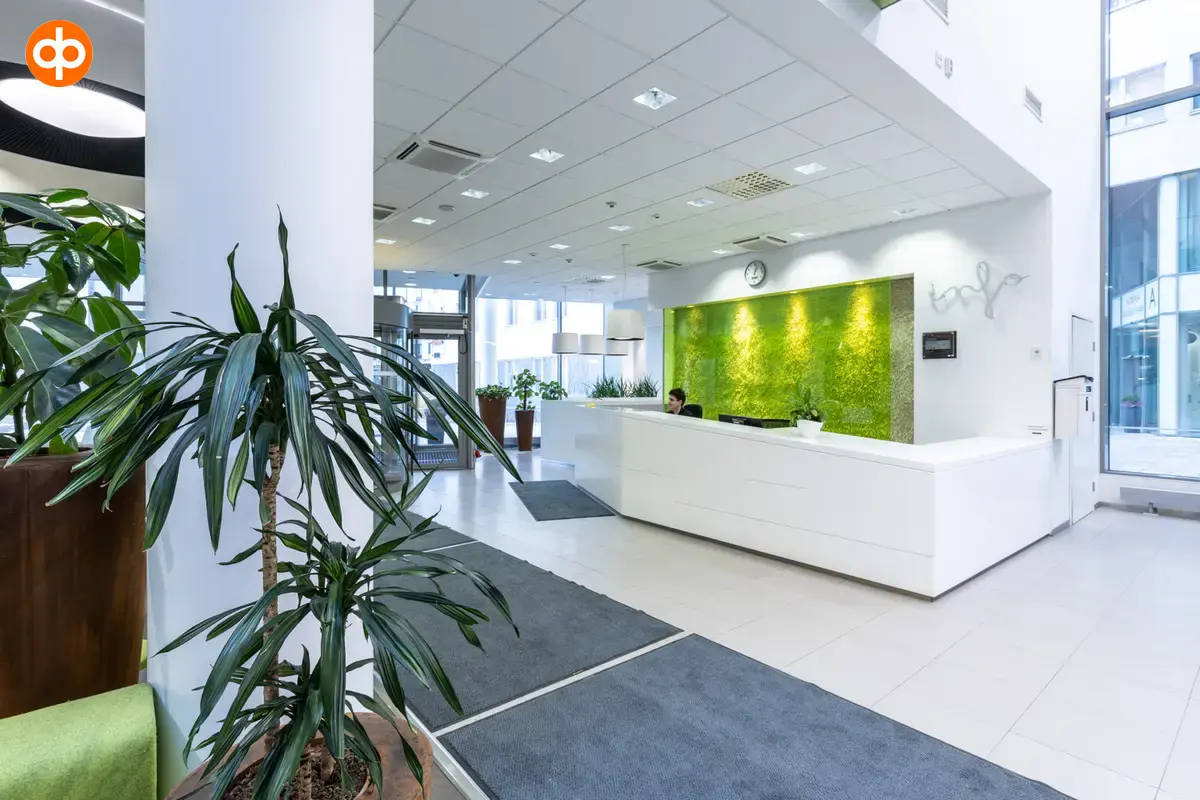 Alberga Business Park – D and E buildings, Lobby of the office building. A white service counter with a light green effect wall behind it. The floors and walls are light, lots of natural light.