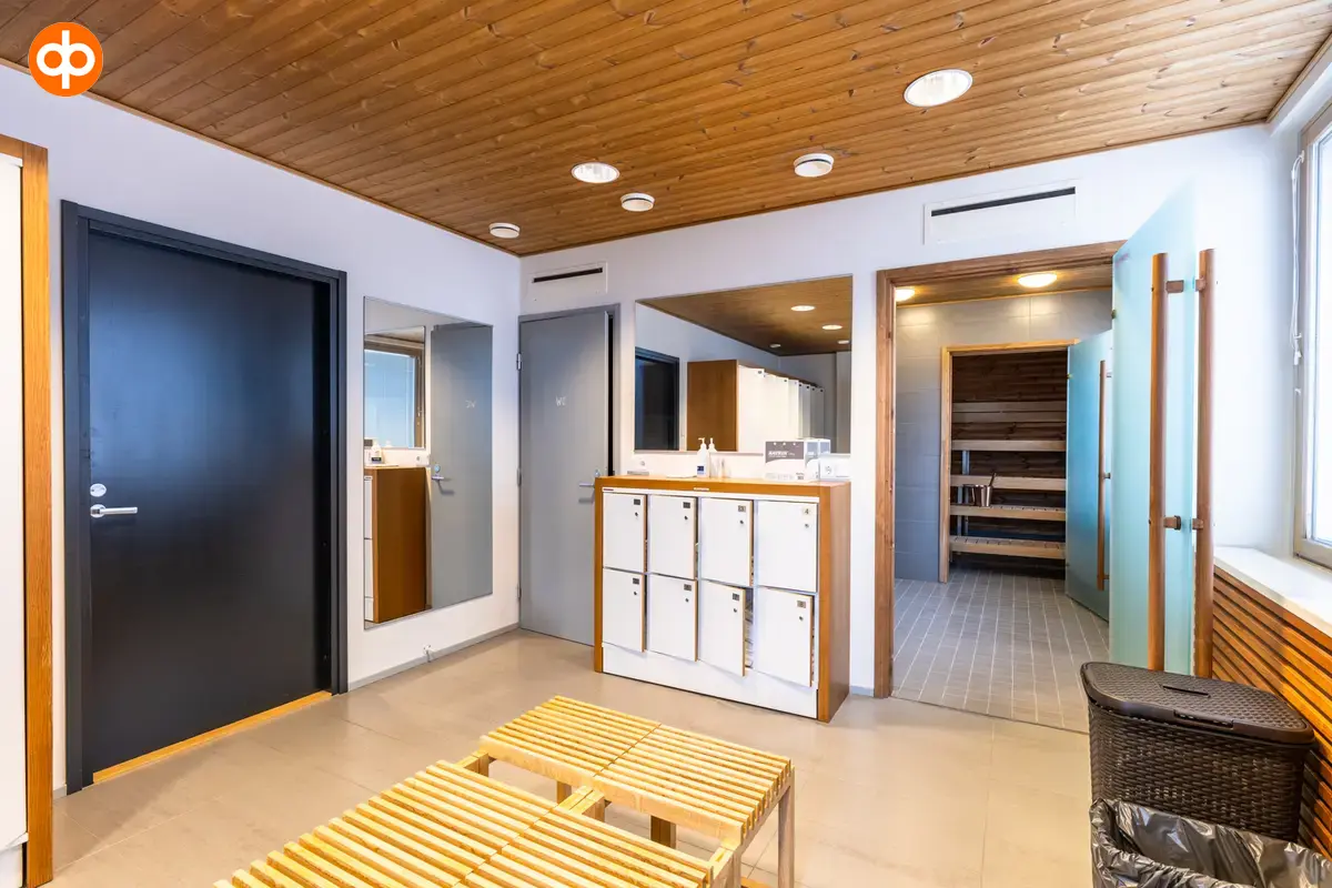 Alberga Business Park – D and E buildings, interior view of the premises. The lounge area of ​​the sauna room. In the middle is a wooden bench, on the back wall are small cabinets.