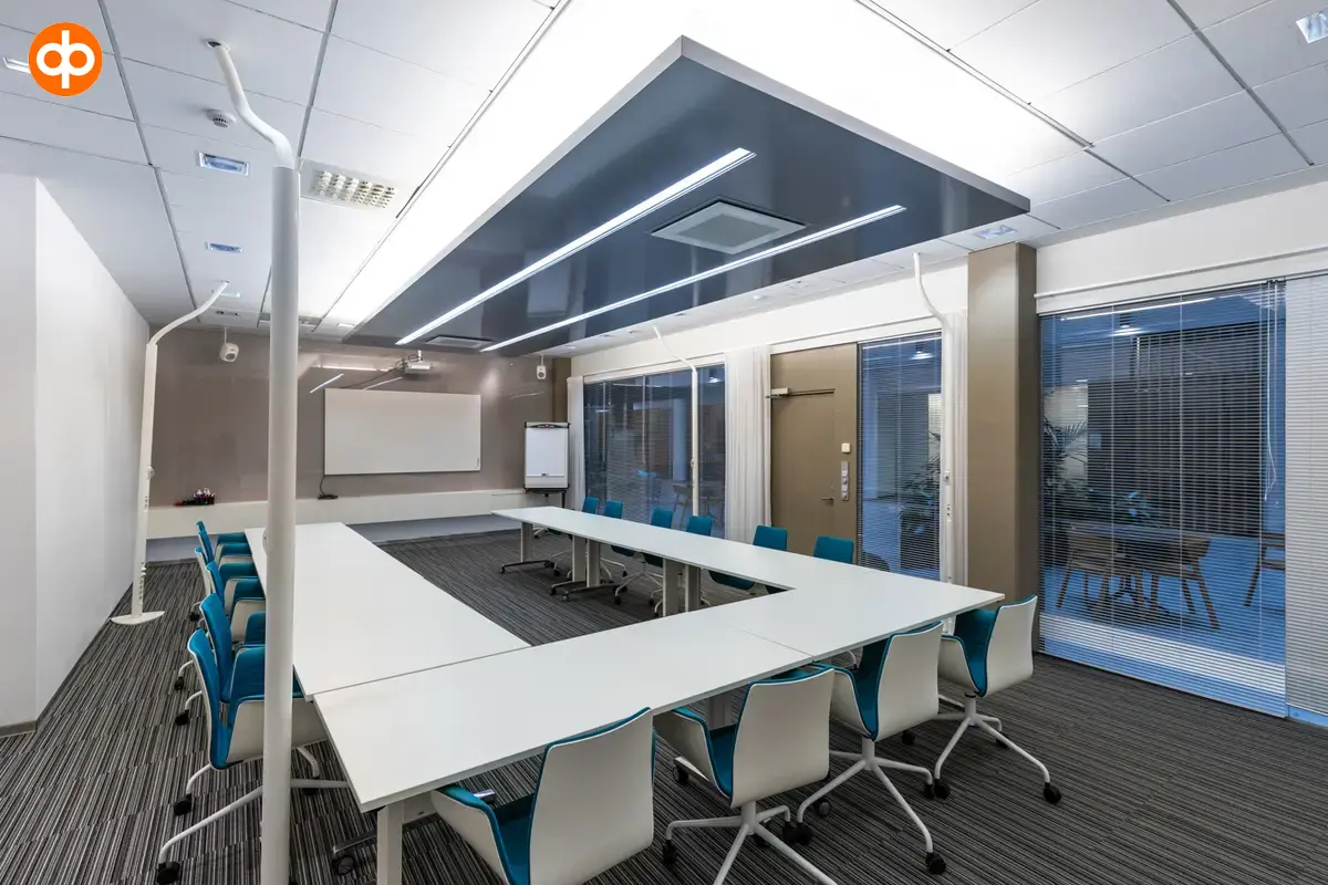 Alberga Business Park, interior view of the office property. A meeting room with a large white table in the middle of the room, surrounded by chairs and a whiteboard on the wall. Floor-to-ceiling wind