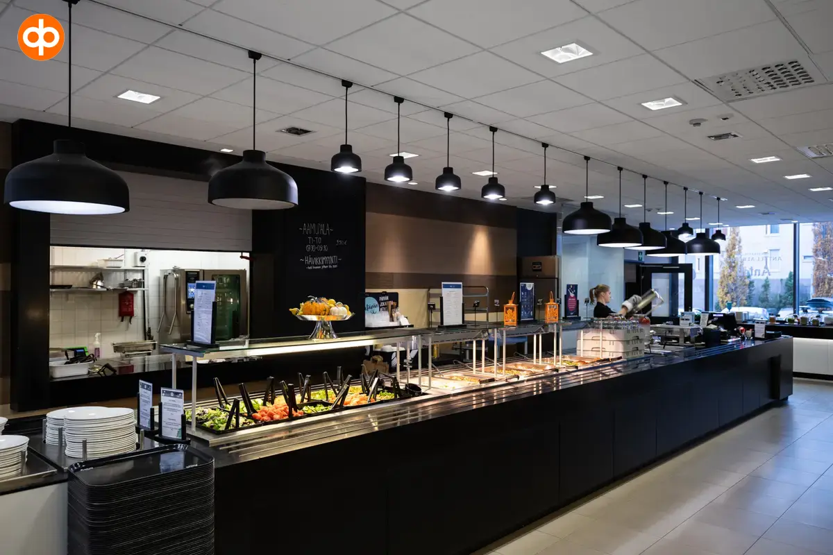 Alberga Business Park, the lunch restaurant of the office property. In the middle, a dark-surfaced food line with the kitchen in the background.