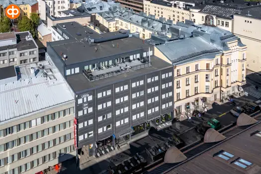 Helsingin Lönnrotinkatu 11, ilmakuva toimitilakiinteistöstä. Tumma monikerroksinen rakennus, jonka vieressä ja takana muita kiinteistöjä. Katutasossa liiketiloja.