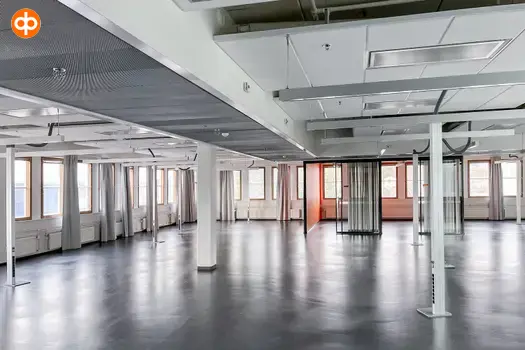 Tietoteknia, interior view of the office space. Empty office space. The space has dark floors and white walls. The space has many columns. Windows on two walls, curtains hanging on the sides