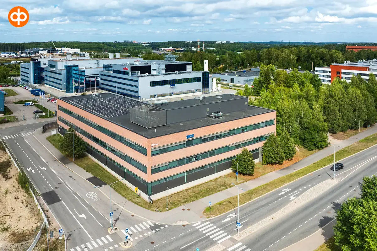 Vantaan Martinkyläntie 17, toimitilakiinteistön ilmakuva. Neliönmuotoinen monikerroksinen talo suuren risteyksen kulmassa, talon julkisivu tiilenoranssi.