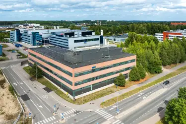 Vantaan Martinkyläntie 17, toimitilakiinteistön ilmakuva. Neliönmuotoinen monikerroksinen talo suuren risteyksen kulmassa, talon julkisivu tiilenoranssi.