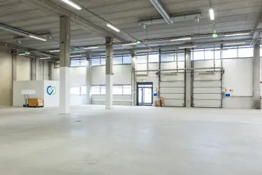 Vantaa Silvastintie 1, interior view of the premises. An empty warehouse with two lifting doors and one glass door next to them. The premises have light surfaces.